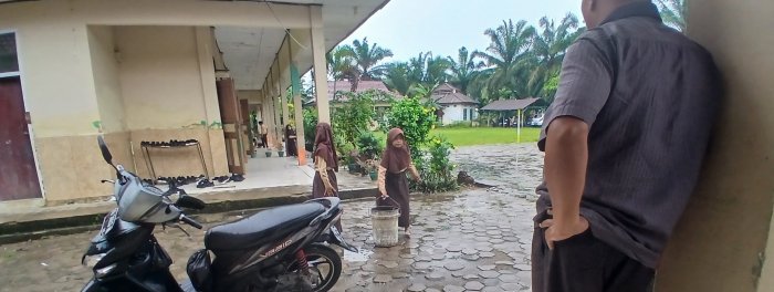Dua Siswi MIN 2 Muaro Jambi Jaga Kebersihan Saat Hujan
